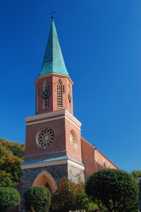 Ceglana wieża kościoła wśród drzew